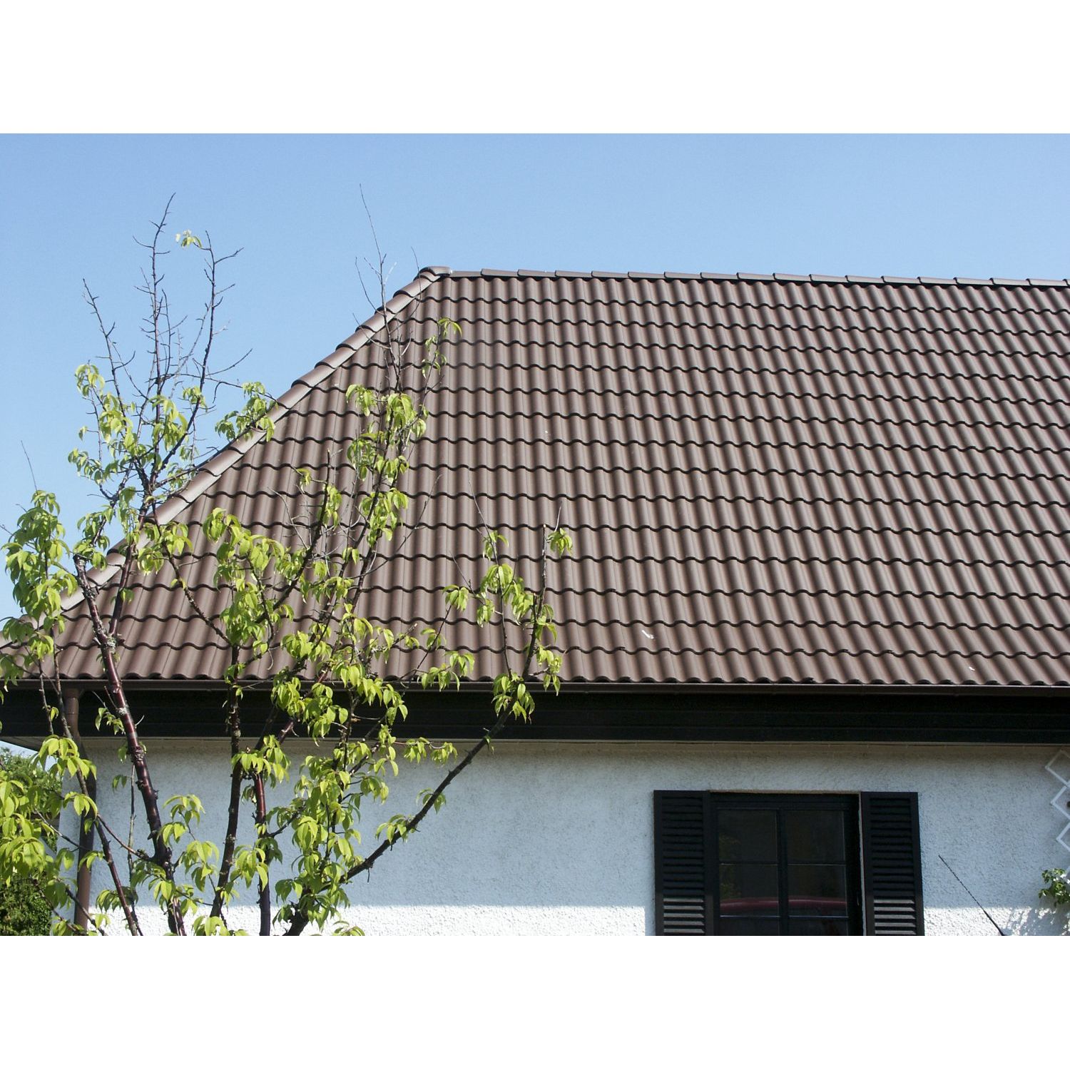 Bendersin ruskea 2-kouruinen Palema-kattotiili sopii hyvin yhteen vaalean rapatun seinäpinnan kanssa