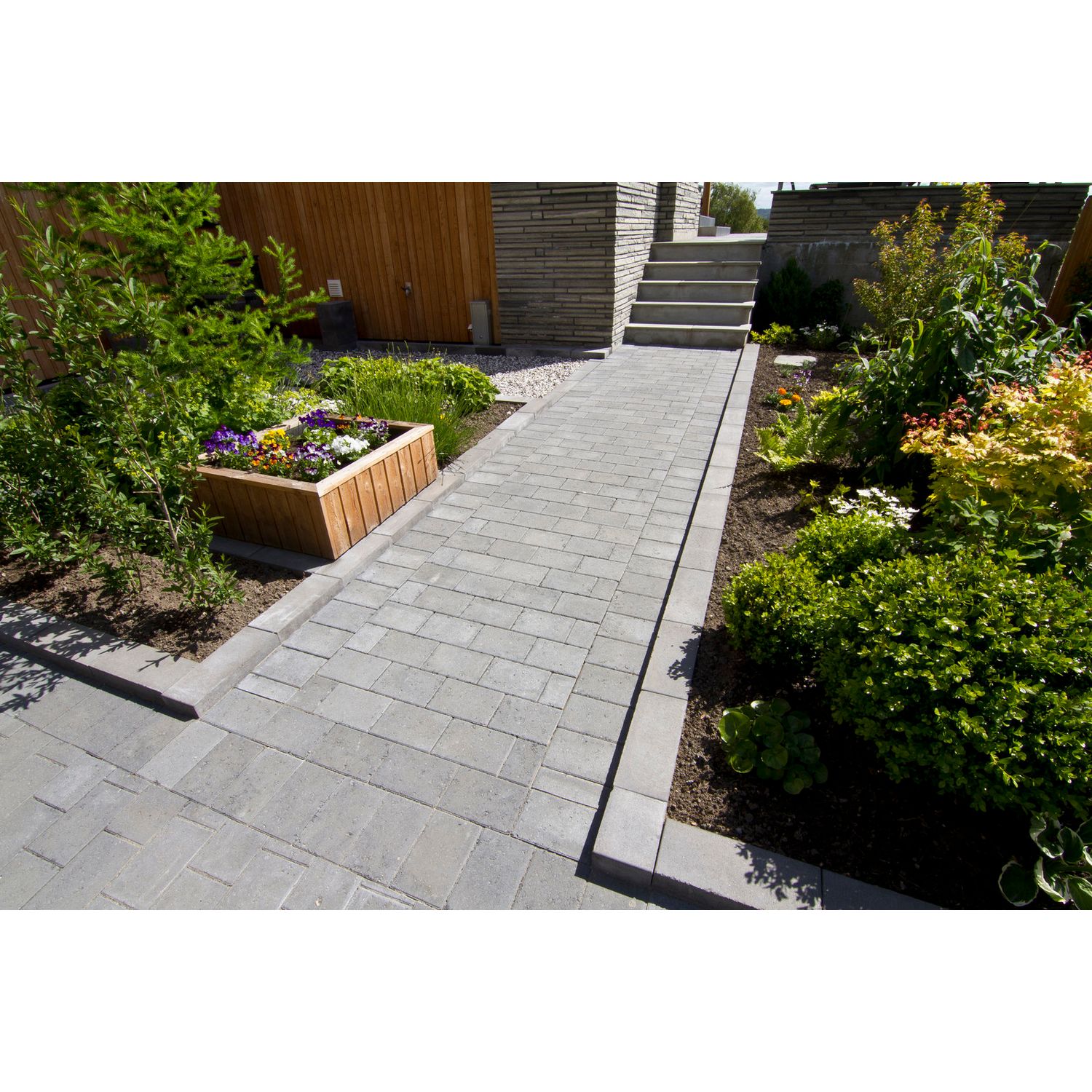 Kukkaistutukset reunustettu grafiitin värisin teräväreunaisin reuna- ja muurikivin